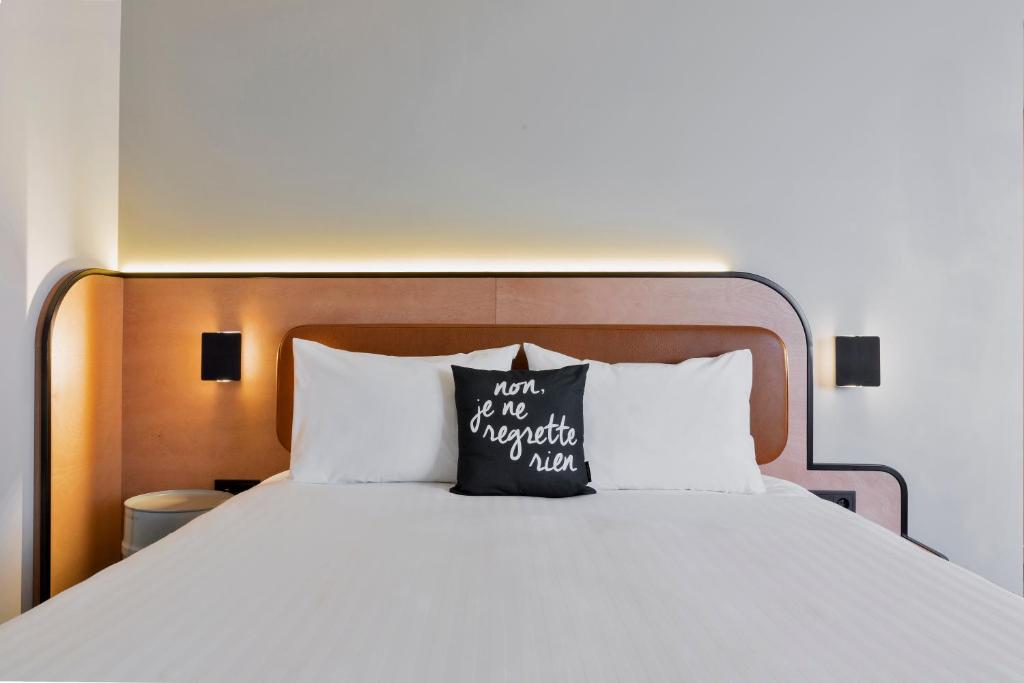 a bed with a pillow that reads not me nor my nationalityaiden at Moxy Paris Bastille in Paris