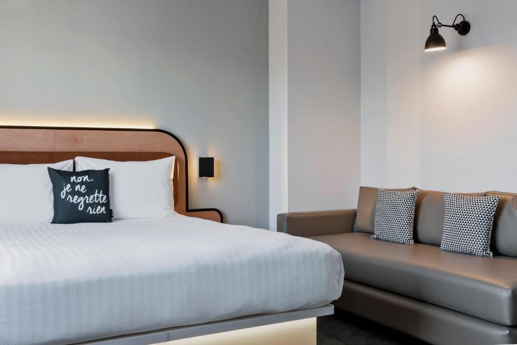 a bedroom with a bed and a couch at Moxy Paris Bastille in Paris