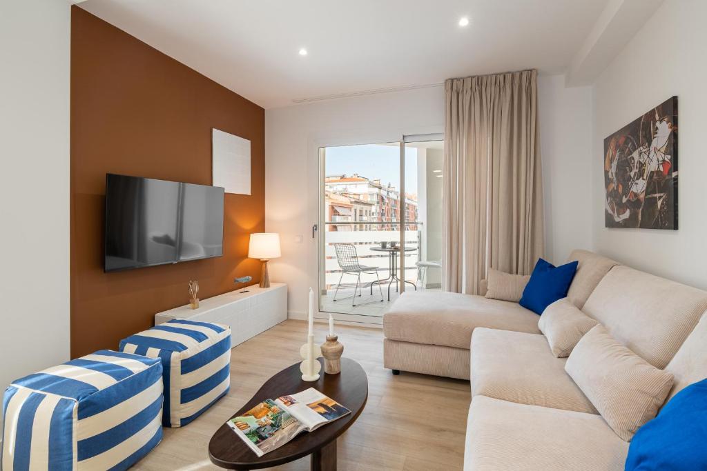 uma sala de estar com um sofá e uma televisão em Calella Apartments by Olala Homes em Calella