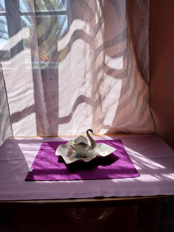un cisne sentado en una servilleta púrpura junto a una ventana en Apartment Surya, en Rogoznica
