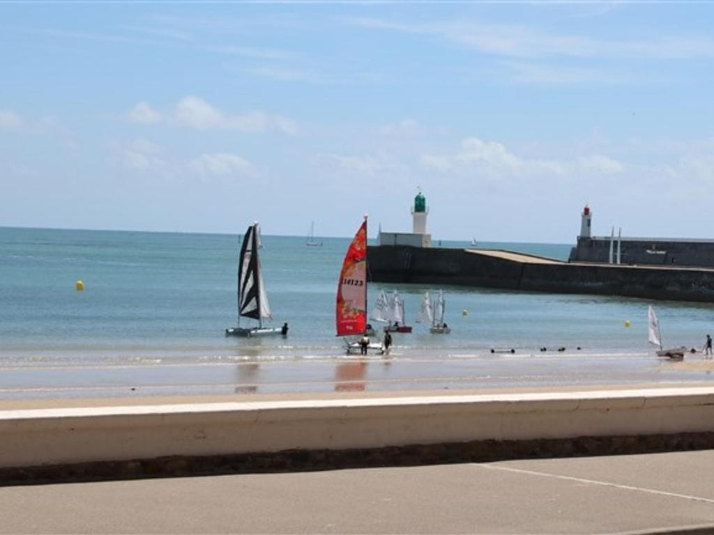 un groupe de voiliers sur une plage avec un phare dans l'établissement Appartement 2 Pièces Rénové Vue Mer, Proche Centre - FR-1-331-84, à Les Sables-dʼOlonne