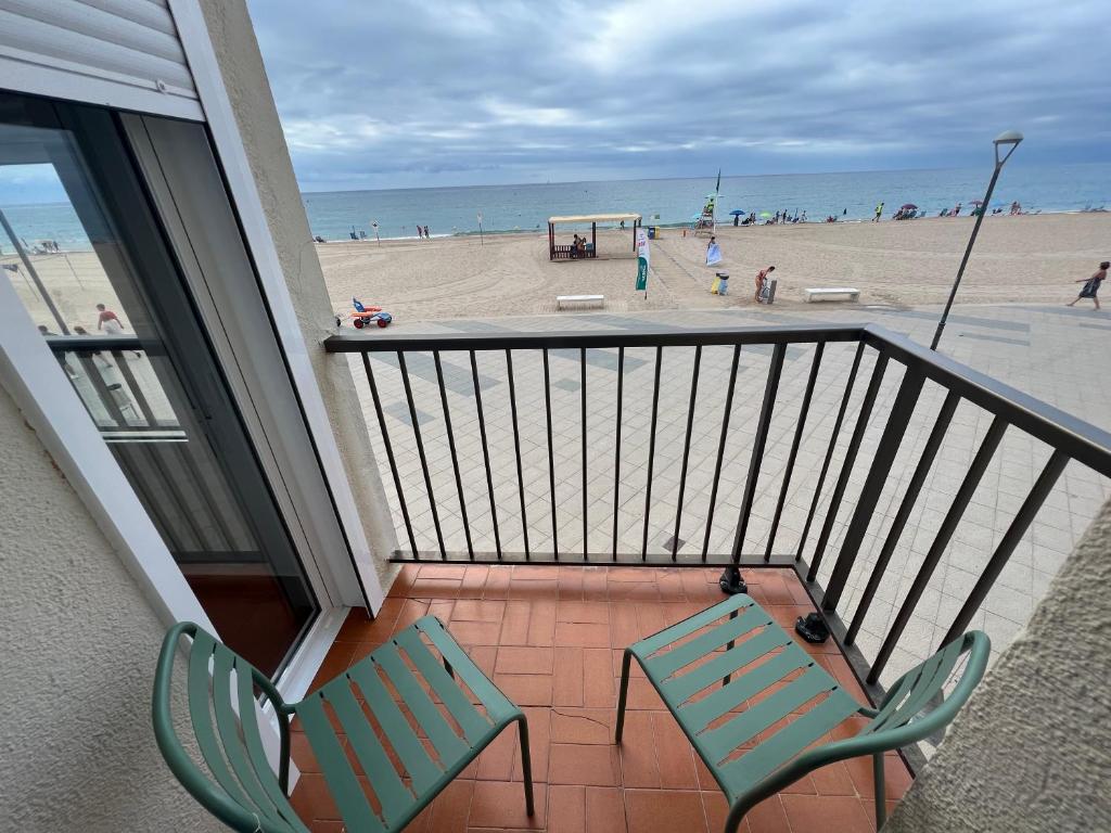 a balcony with two chairs and a beach at El Popet de Baix a Mar in Torredembarra