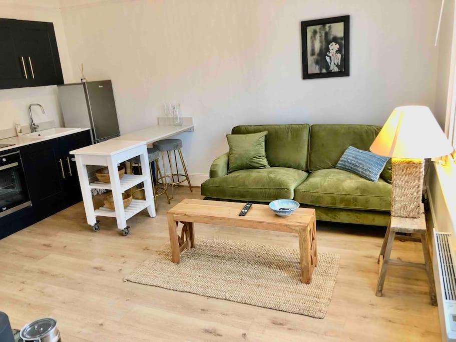 a living room with a green couch and a table at A perfectly located bright, modern ,Victorian flat in Royal Tunbridge Wells