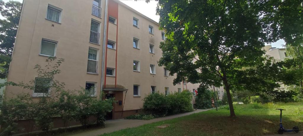 un edificio de apartamentos con un árbol delante de él en Warszawa Wola Pokoje en Varsovia