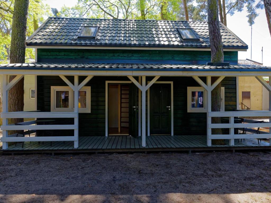 a small green cabin with a porch in the woods at Holiday house in Pobierowo for 4 people near the sea in Pobierowo