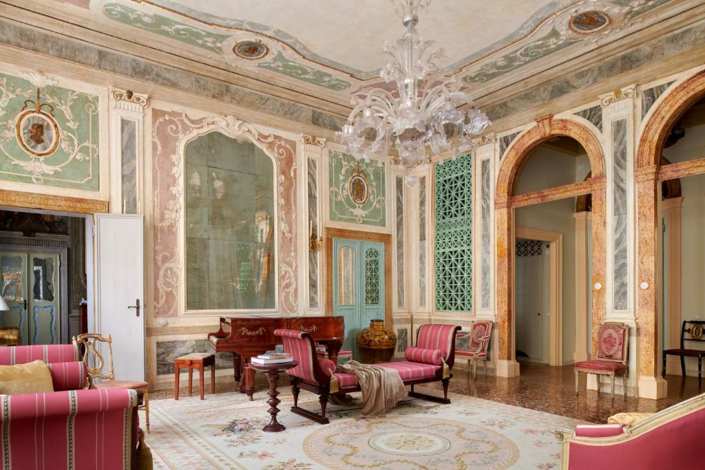 sala de estar con lámpara de araña y paredes rosas en Imperiale Piano Nobile, en Venecia