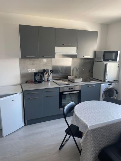 a kitchen with gray cabinets and a table with a chair at Charmant appartement avec parking privée in Buxerolles