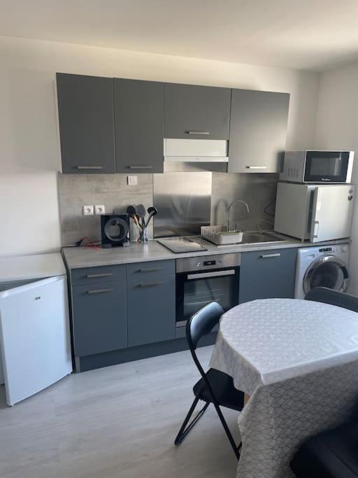 BuxerollesCharmant appartement avec parking privée的厨房配有灰色橱柜和桌椅