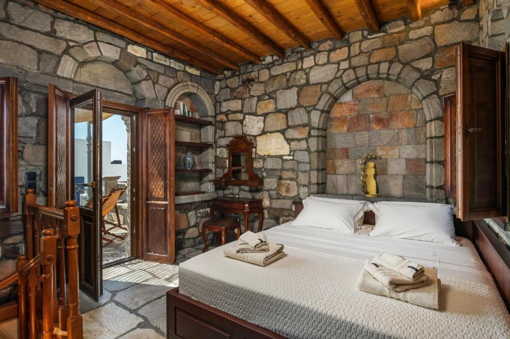1 dormitorio con 1 cama en una pared de piedra en The Treasure Box - Private Stone Villa, en Plaka Milou
