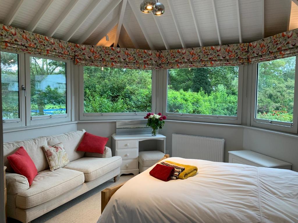 a bedroom with a bed and a couch and windows at Brookfield Cottage in West Kirby