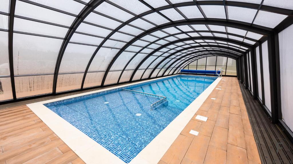 an indoor swimming pool with a glass ceiling at Flatbook Apartamenty - Sztutowo Baltic Sun -B-I- in Sztutowo