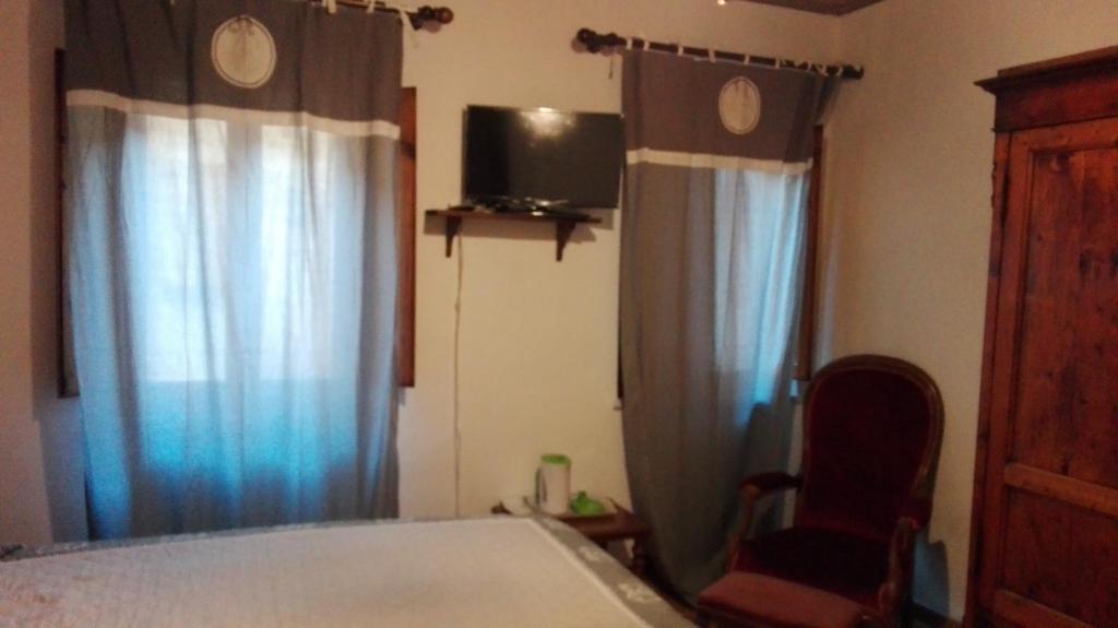um quarto com uma cama, cortinas e uma cadeira em B&B La Fontanina em Siena