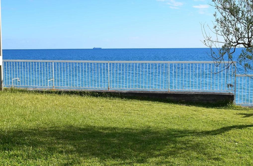 una cerca azul con el océano en el fondo en Appartamento Letojanni Gabbiano Sul Mare, en Letojanni