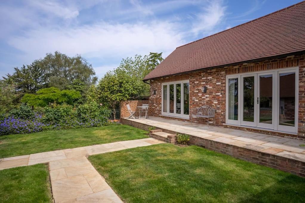 a brick house with a patio and a yard at Greentrees Estate -The Oak Suite in Haywards Heath