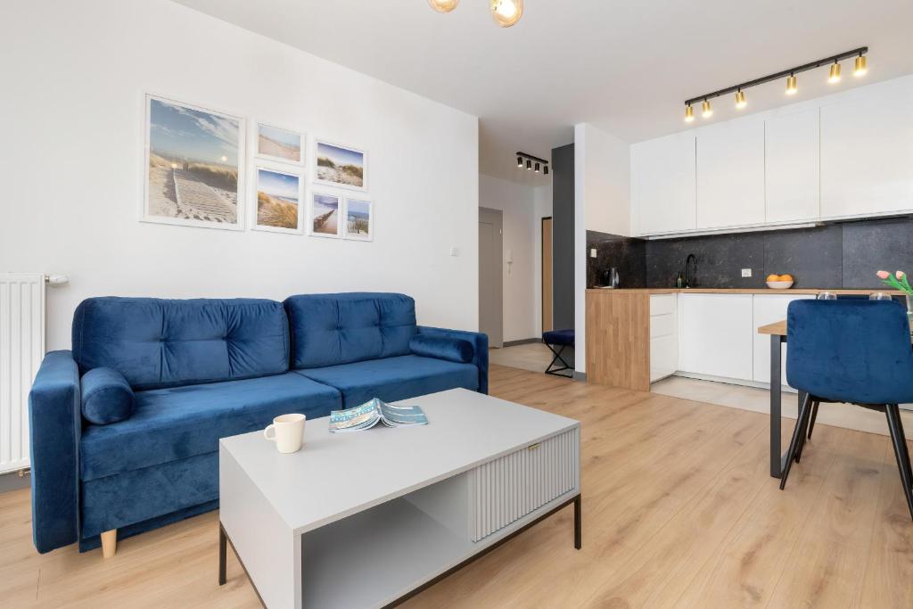 a living room with a blue couch and a table at Apartment Starowiejska with Balcony & Parking next to Gdańsk Arena Stadium by Renters in Gdańsk