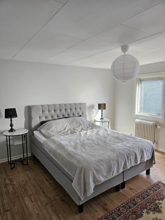 a white bedroom with a large bed and two tables at Villa Sandgatan in Falkenberg