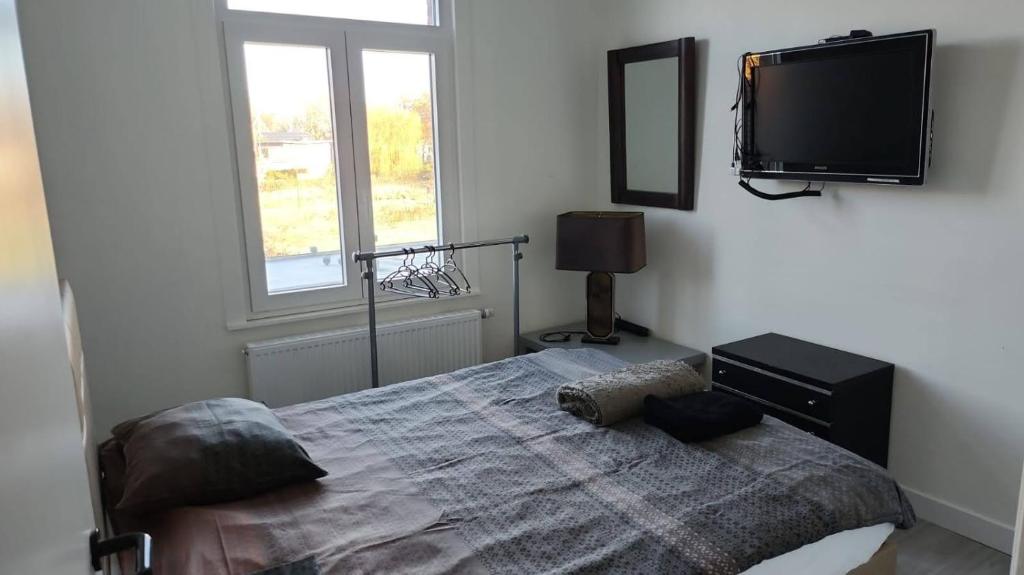 een slaapkamer met een bed en een flatscreen-tv bij Mechelen Room living with host in Mechelen