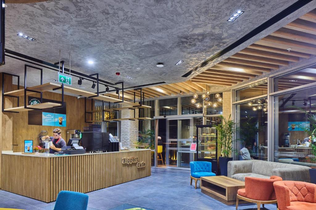 un hall d'entrée avec un comptoir, des chaises et une personne dans l'établissement Ibis Istanbul Airport, à Istanbul