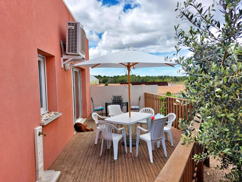 a patio with a table and chairs and an umbrella at Villa 6 personnes dans résidence calme, grande terrasse, 5 mn de la plage in Fleury