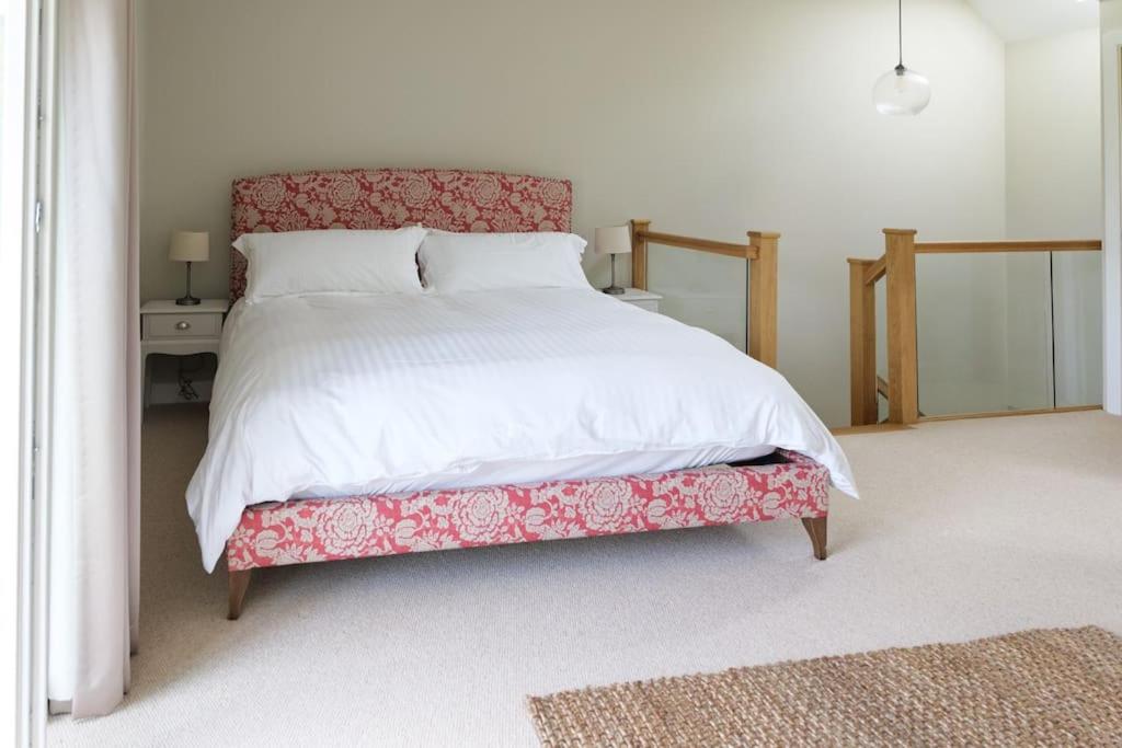 a bedroom with a bed with a red and white comforter at Greentrees Estate - The Chestnut Cottage in Balcombe