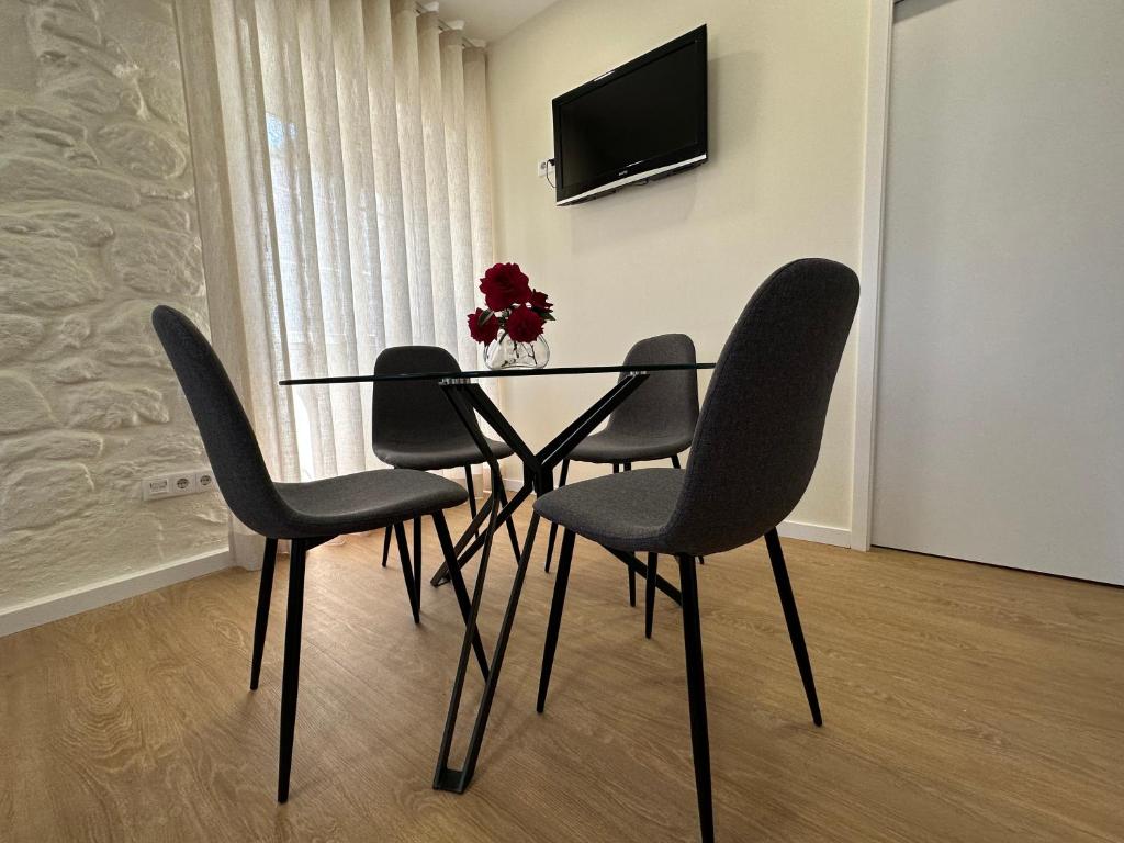 a dining room table with four chairs and a television at Casa da Poça 2 - Guest House in Braga