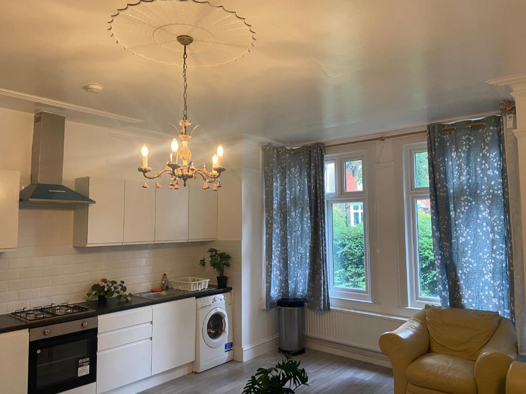 a kitchen with a chandelier and a living room at Homely 3 Bedroom Ground Floor Flat in London