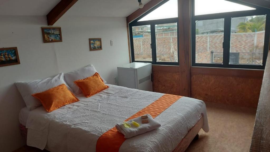 a bedroom with a bed with orange pillows and a window at Casa Playa San Jacinto Manabi in San Jacinto