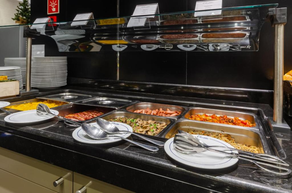 a buffet line with many trays of food and spoons at Olissippo Marquês de Sá in Lisbon