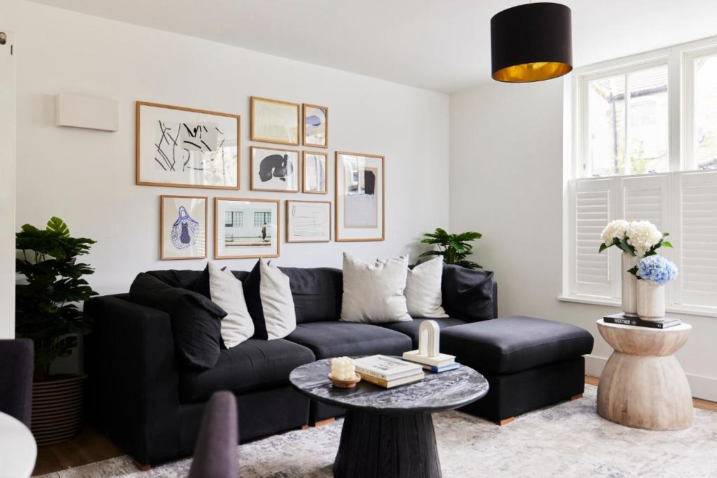 a living room with a black couch and a table at The Ravenscourt Park Escape - Bright 2BDR Flat in London