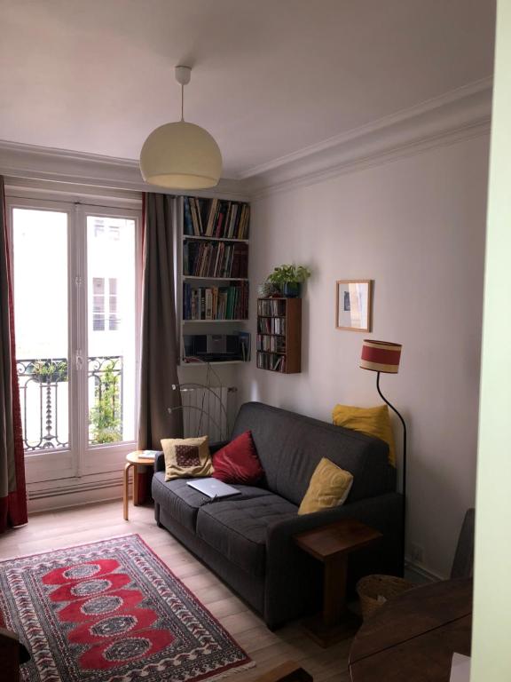 un salon avec un canapé et une fenêtre dans l'établissement Nice and practical apartment to enjoy Paris close to Montmartre, à Paris