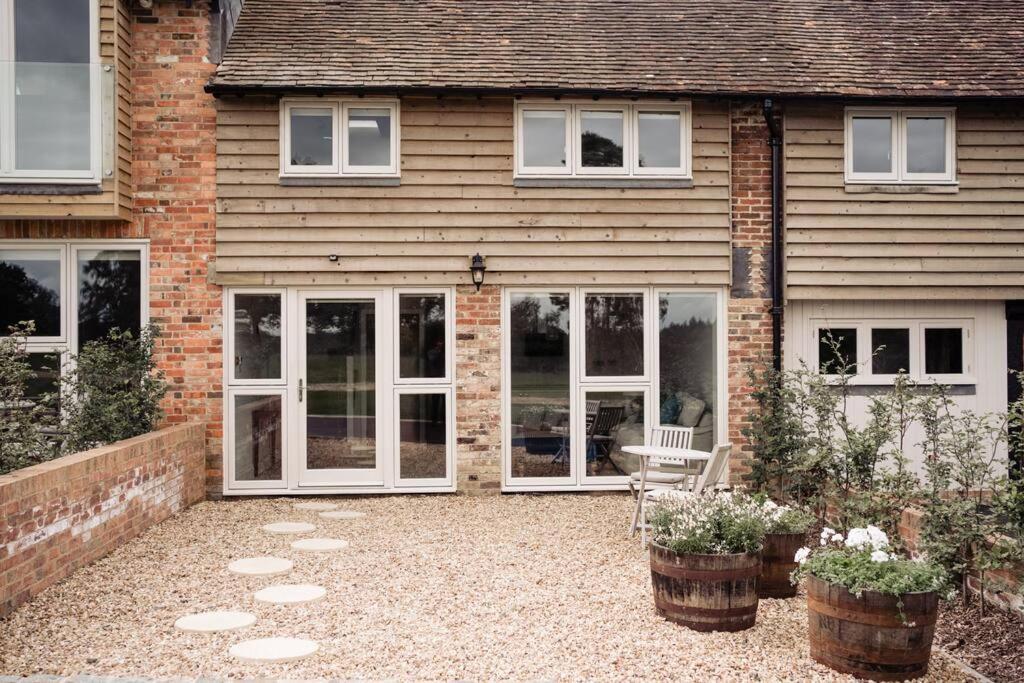 a house with sliding glass doors and a patio at Greentrees Estate - The Beech Cottage in Haywards Heath