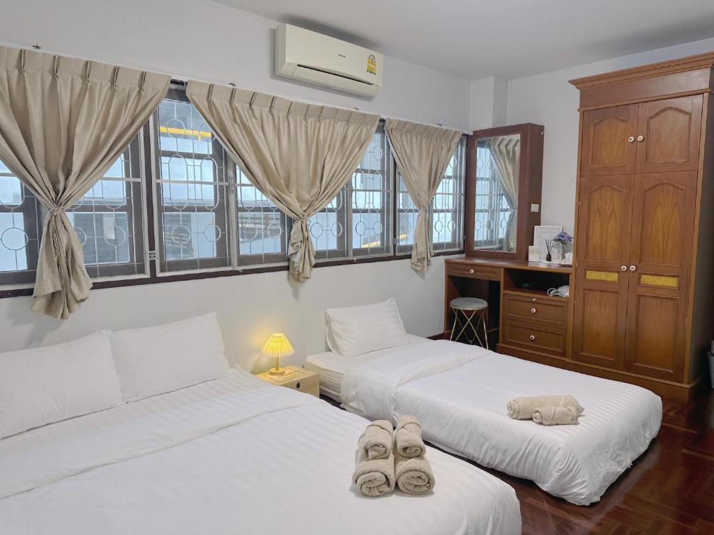 a bedroom with two beds and a desk and windows at Kong Khong Homestay in Hat Yai