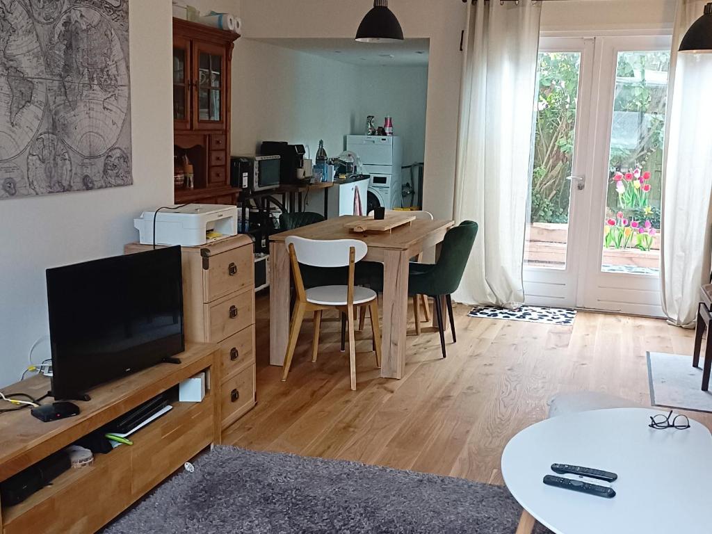 een woonkamer met een televisie en een tafel met stoelen bij Double room in private home in Zaandam