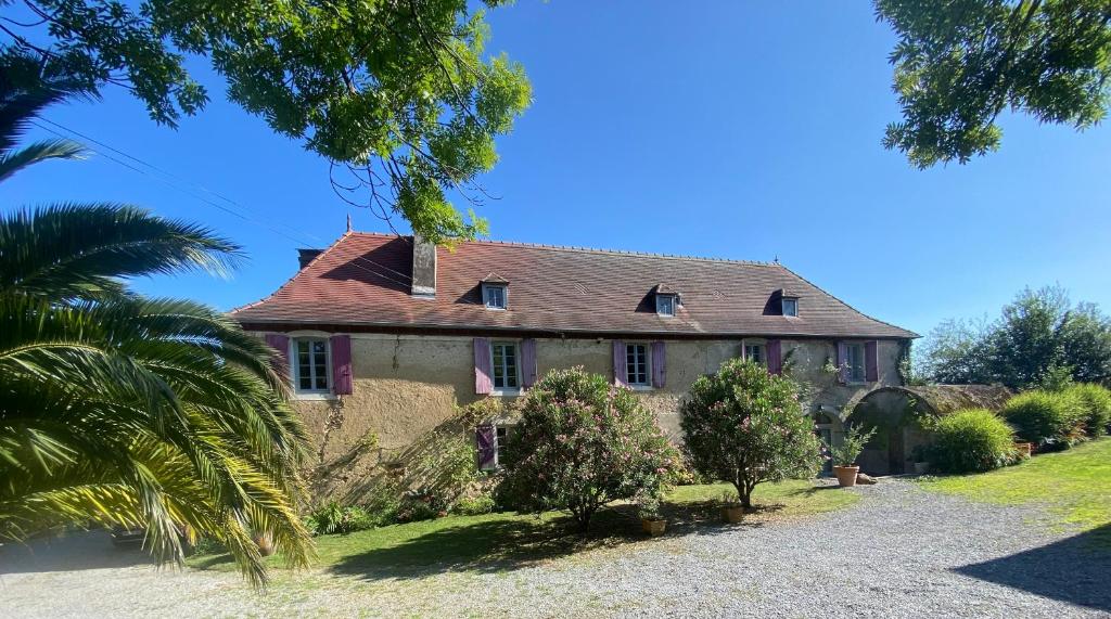 una casa vieja con una palmera delante de ella en Maison Castaings, en Lucq-de-Béarn