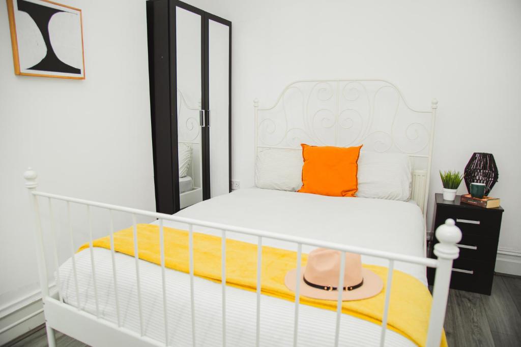 a bedroom with a white bed with an orange pillow at Modern Central Oasis in Liverpool