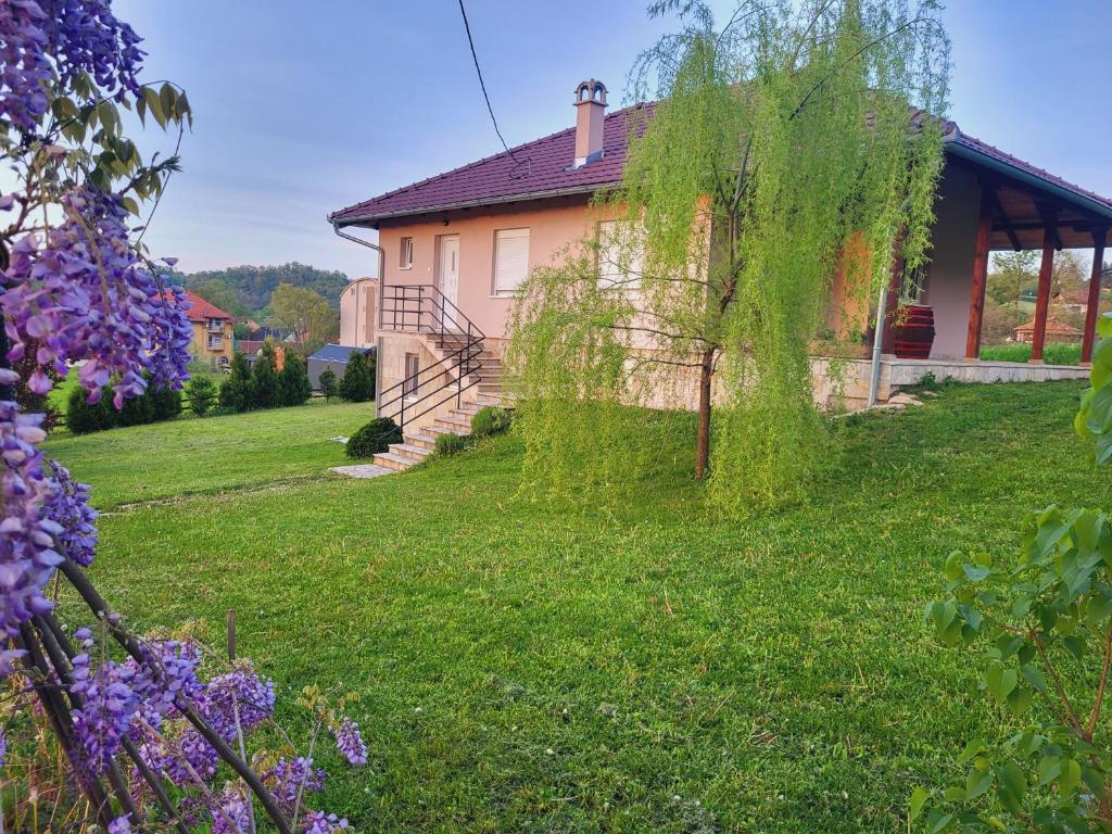 a house in a yard with grass and purple flowers at Apartman MatiNik1 in Gornja Toplica