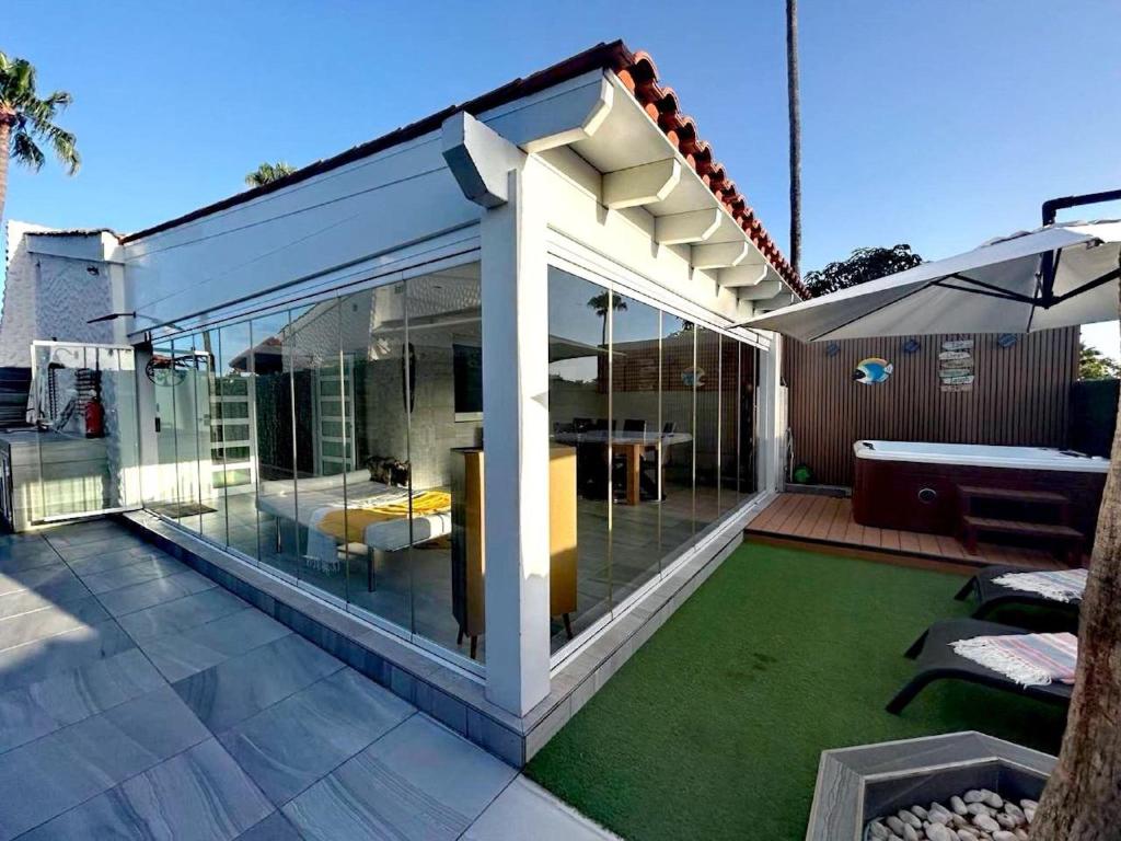 eine Glaserweiterung eines Hauses mit einer Terrasse in der Unterkunft Chalet Privato con Jacuzzi New in Maspalomas