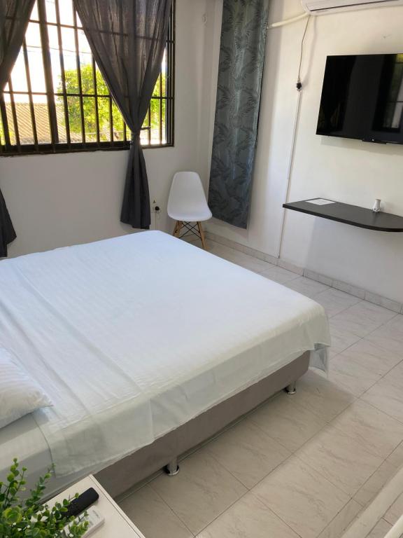 um quarto com uma cama branca e uma televisão em Habitaciones independientes cerca al aeropuerto 3 em Cartagena de Indias