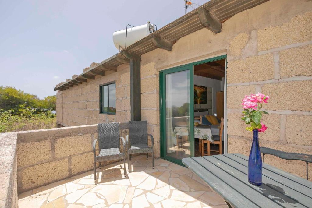 a patio with a table and two chairs and a vase of flowers at Casa Killa in Granadilla de Abona