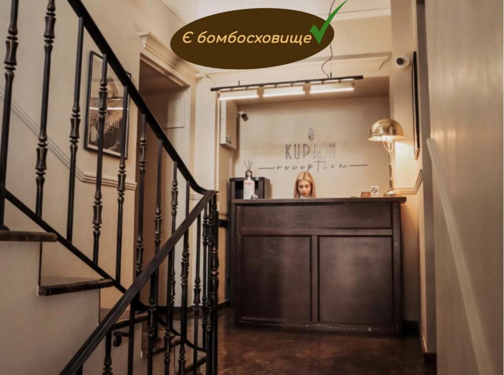 une femme debout à un comptoir dans une pièce dans l'établissement Kuprin Hotel, à Odessa