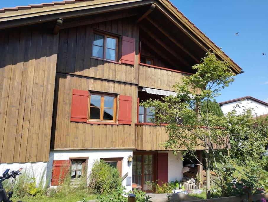 ein großes Holzhaus mit roten Fensterläden in der Unterkunft Ferienhaus: idyllisch & erholsam in Eglofs