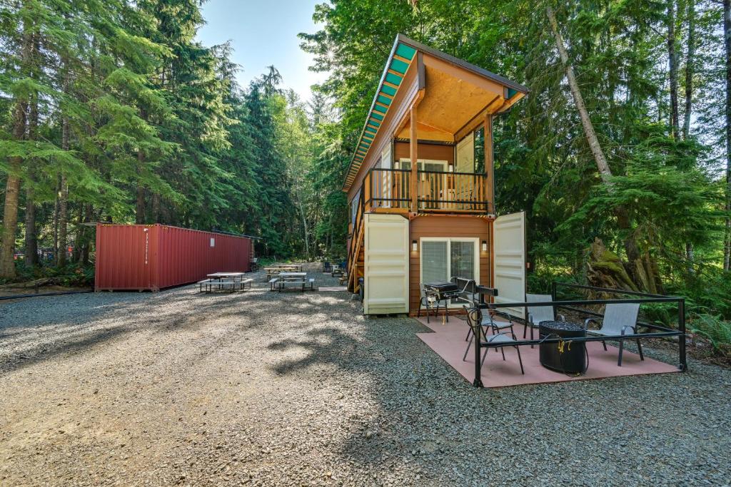 una cabaña en el bosque con mesa y sillas en Unique Container Studio with Deck and Fire Pit! en Buckley