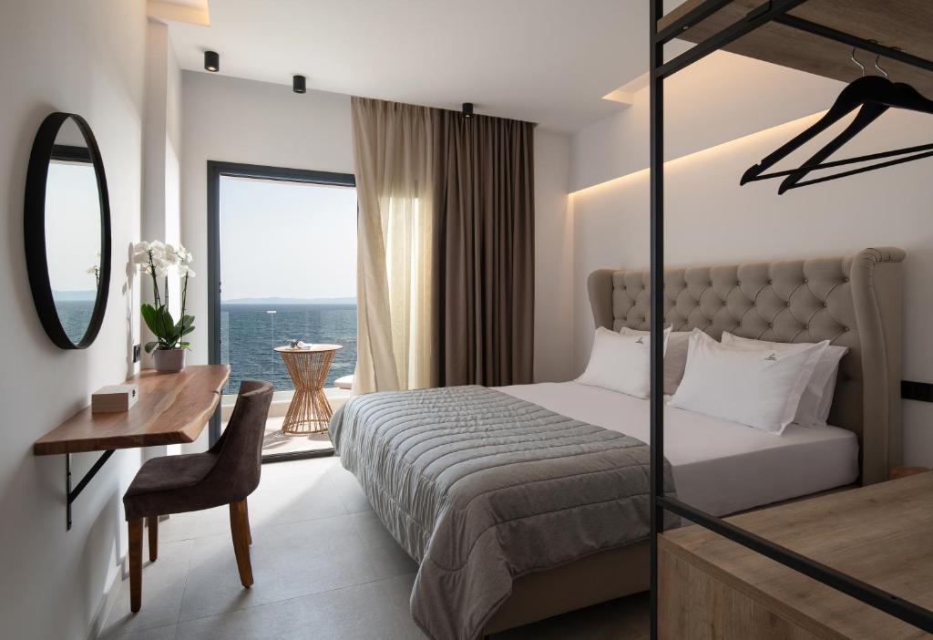 a bedroom with a bed and a desk and a window at G Mare Boutique Hotel in Neos Marmaras