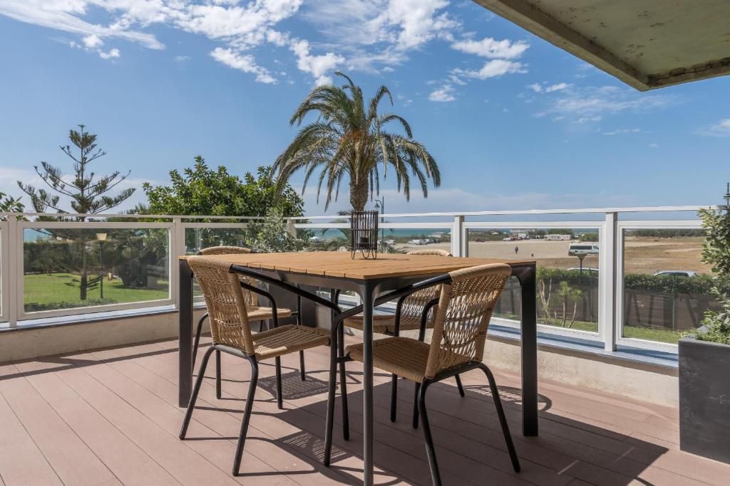 einen Tisch und Stühle auf einem Balkon mit Blick auf den Strand in der Unterkunft Suite Homes Hesperides garden beach in Málaga