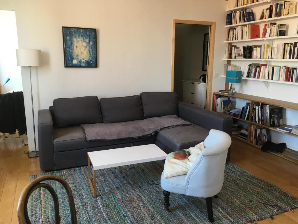 een woonkamer met een bank en een stoel bij 3 Pièces lumineux et calme 44m2 Les Lilas in Les Lilas