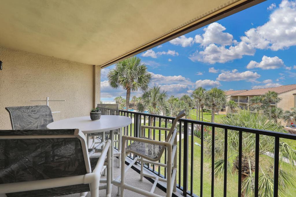 a balcony with a table and chairs and palm trees at Modern oceanfront condo with two pools & private washer/dryer in Saint Augustine