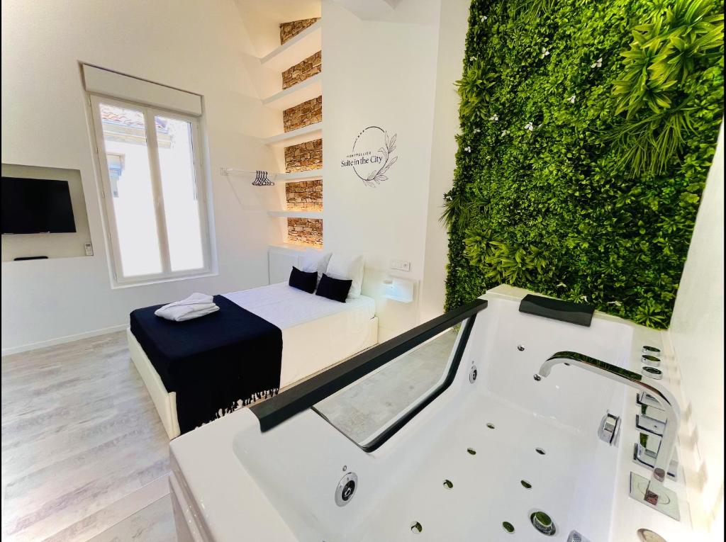 Suite in the City - Standing Hyper-centre JACUZZI CLIM WIFI في مونبلييه: حمام مع حوض استحمام وجدار أخضر