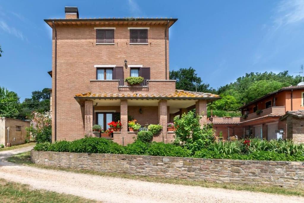 a brick house with flowers in the window at La collina degli Olivi in Spina