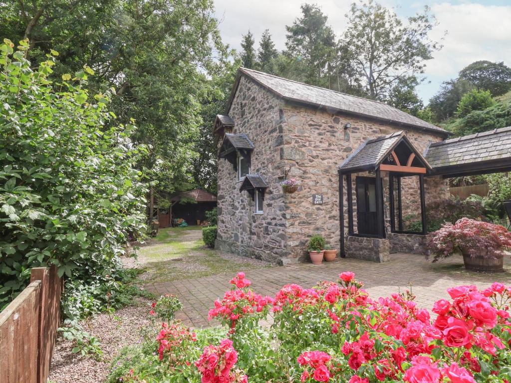 a stone building with flowers in front of it at The Old Barn in Mold