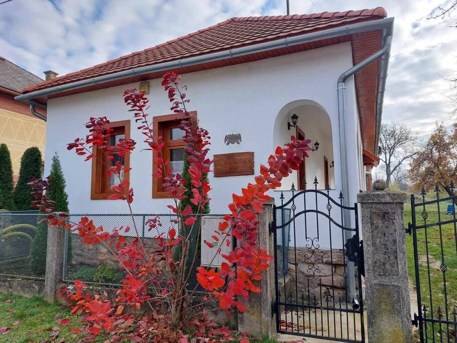 a small white house with red windows and a fence at Menedék - testnek és léleknek 
